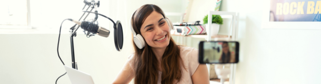 A young girl has a phone set-up to record with a radio host-style microphone.